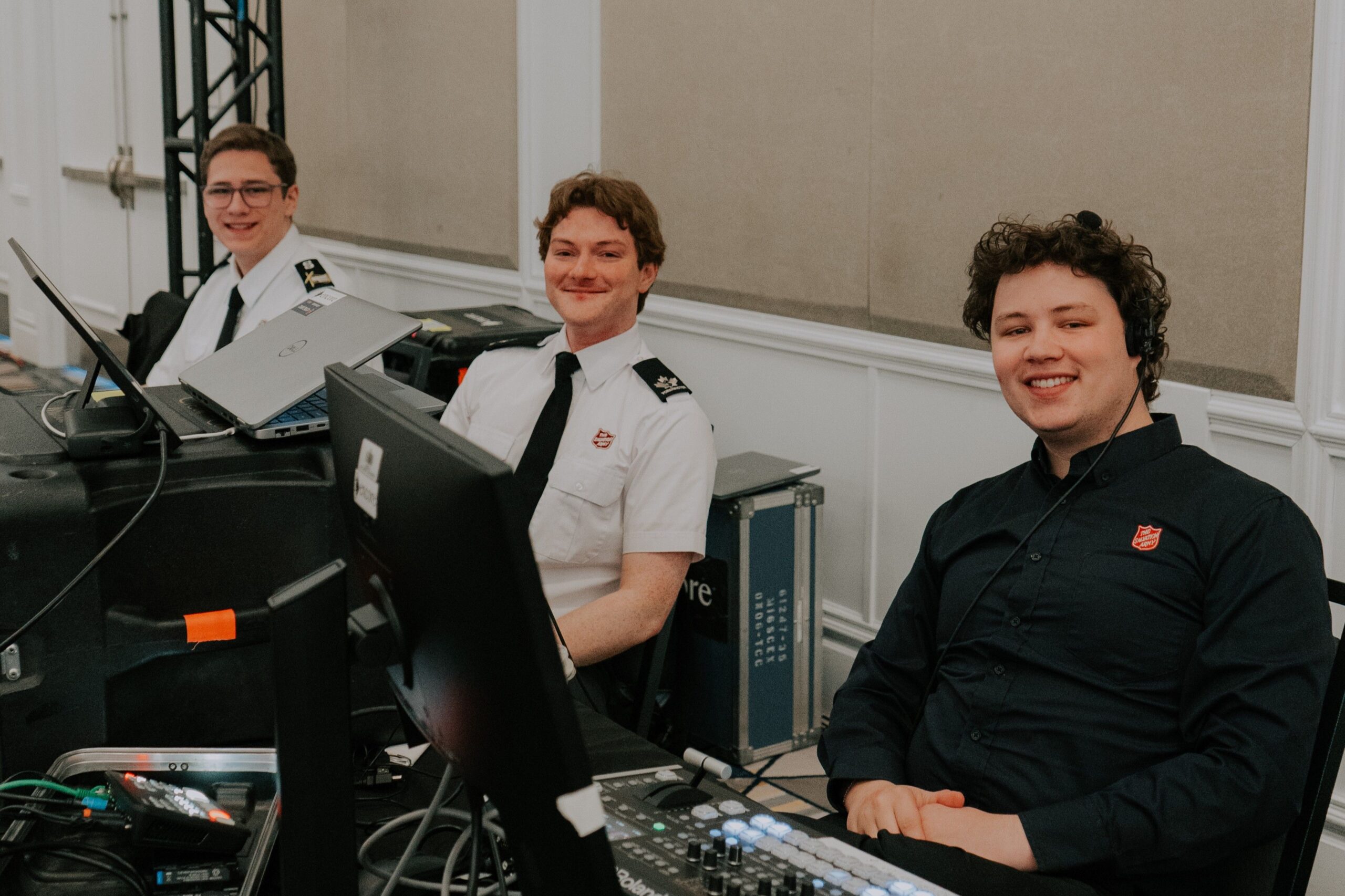 3 guys sitting at production booth in salvation army attire